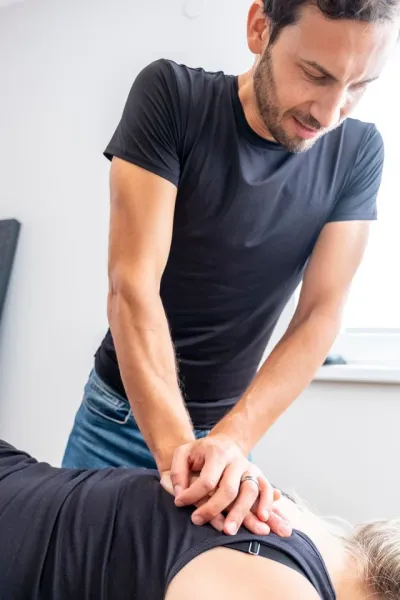 Physiotherapeut behandelt den Rücken einer Patientin mit manueller Therapie.